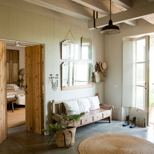 Immagine di un grande ingresso o corridoio country con pareti beige, pavimento in cemento e una porta in vetro