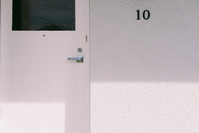 Imagen de puerta principal clásica de tamaño medio con paredes grises, suelo de baldosas de porcelana, puerta simple, puerta blanca y suelo gris