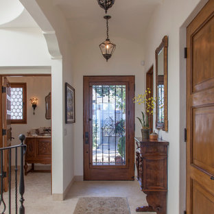 Esempio di un ingresso mediterraneo di medie dimensioni con pareti bianche, pavimento in travertino, una porta singola e una porta in legno bruno