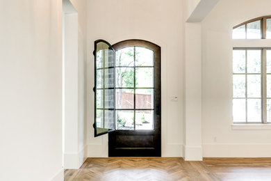 Example of a transitional medium tone wood floor and brown floor entryway design in Dallas with white walls and a black front door