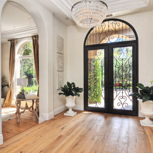 Ispirazione per un ingresso classico con pareti beige, parquet chiaro, una porta a due ante e una porta in vetro