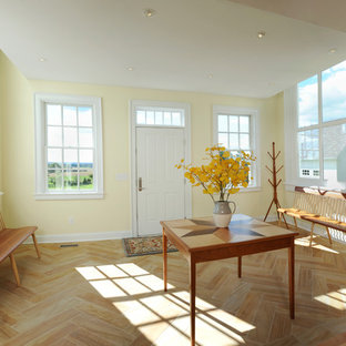 Inspiration for a mid-sized country light wood floor entryway remodel in Columbus with yellow walls and a white front door