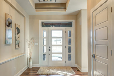 Diseño de hall actual de tamaño medio con paredes beige, suelo de madera oscura, puerta simple y puerta de vidrio
