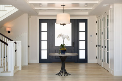 サンディエゴにある広いトランジショナルスタイルのおしゃれな玄関ロビー (淡色無垢フローリング、黒いドア、白い壁、ベージュの床) の写真