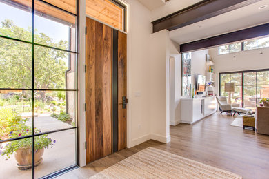 Imagen de distribuidor contemporáneo con paredes blancas, suelo de madera en tonos medios, puerta simple y puerta de madera en tonos medios