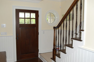 Diseño de puerta principal marinera pequeña con paredes amarillas, suelo de madera oscura, puerta simple, puerta de madera oscura y suelo marrón