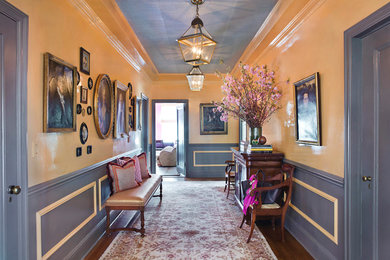 Imagen de hall tradicional de tamaño medio con paredes amarillas, suelo de madera en tonos medios, puerta simple y puerta azul