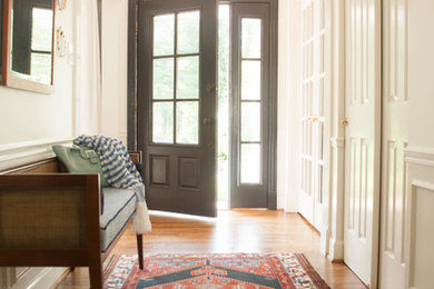 Foto de distribuidor clásico pequeño con paredes blancas, suelo de madera en tonos medios, puerta simple y puerta negra
