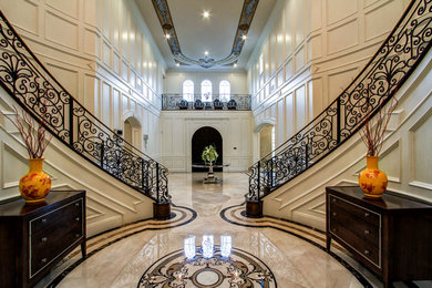 Example of a huge classic marble floor entryway design in Los Angeles with white walls and a dark wood front door