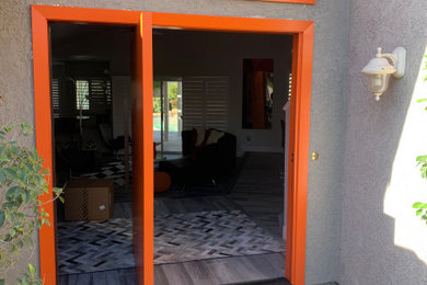 他の地域にある高級な広いコンテンポラリースタイルのおしゃれな玄関ドア (グレーの壁、コンクリートの床、オレンジのドア、白い床) の写真