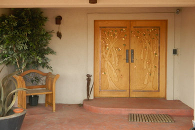 デンバーにあるラグジュアリーな広いサンタフェスタイルのおしゃれな玄関ドア (白い壁、コンクリートの床、木目調のドア) の写真