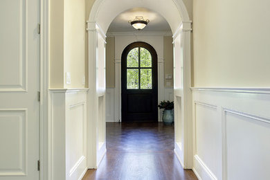 Example of a mid-sized classic medium tone wood floor entryway design in Chicago with beige walls and a dark wood front door