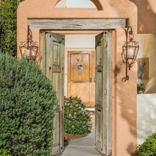 Idee per una porta d'ingresso mediterranea con pareti arancioni, una porta a due ante e una porta in legno bruno
