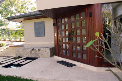 Cette photo montre une porte d'entrée tendance de taille moyenne avec un mur beige, tomettes au sol, une porte double, une porte en bois brun et un sol beige.