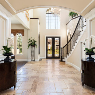 Ispirazione per un grande ingresso chic con pareti beige, una porta a due ante, una porta in legno scuro, pavimento beige e pavimento in pietra calcarea