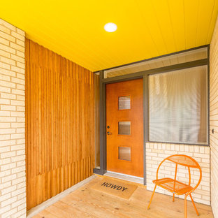 Réalisation d'une porte d'entrée vintage de taille moyenne avec un mur multicolore, un sol en contreplaqué, une porte simple et une porte en bois brun.