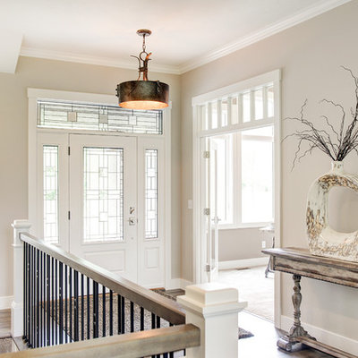 Example of a mid-sized transitional medium tone wood floor entryway design in Other with beige walls and a white front door