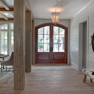 Idée de décoration pour un grand hall d'entrée ethnique avec un mur blanc, un sol en bois brun, une porte double et une porte en verre.