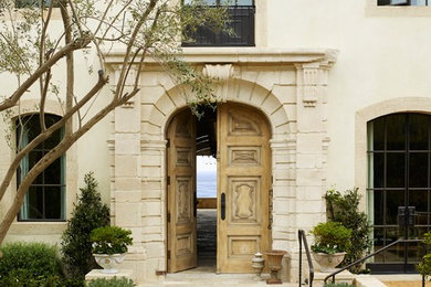 На фото: входная дверь в средиземноморском стиле с двустворчатой входной дверью и входной дверью из светлого дерева