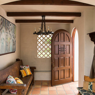 Mittelgroßer Mediterraner Eingang mit Stauraum, beiger Wandfarbe, Terrakottaboden, Einzeltür und dunkler Holztür in Los Angeles