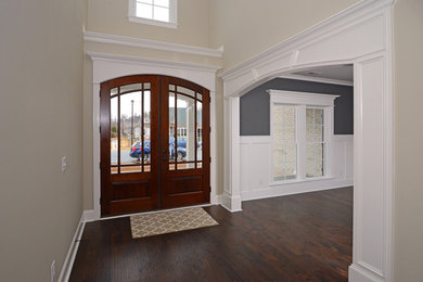 Example of a large medium tone wood floor entryway design in Other with beige walls and a dark wood front door