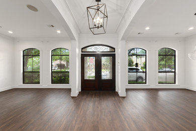 Large transitional laminate floor and brown floor entryway photo in Houston with white walls and a dark wood front door