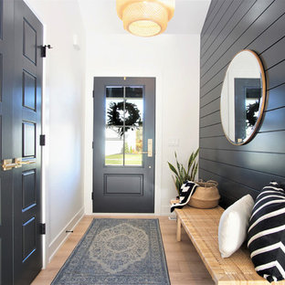 Idée de décoration pour une entrée nordique de taille moyenne avec un sol en bois clair, une porte simple, une porte noire, un mur noir, un couloir et un sol beige.