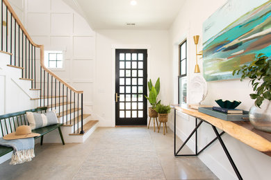 Beach style concrete floor entryway photo in Other with white walls and a black front door