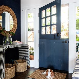Cette photo montre une porte d'entrée bord de mer de taille moyenne avec un mur blanc, un sol en bois foncé, une porte double et une porte bleue.