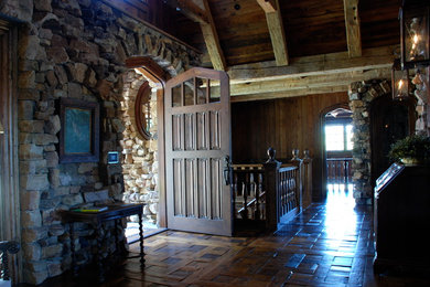 Idée de décoration pour un grand hall d'entrée tradition avec un mur marron, parquet foncé, une porte simple et une porte en bois foncé.