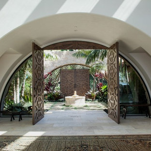 Inspiration for a huge mediterranean limestone floor entryway remodel in Orange County with white walls and a medium wood front door