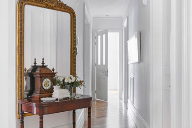 Imagen de hall clásico con paredes blancas, suelo de madera en tonos medios y suelo marrón