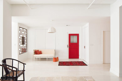 Modern inredning av en ingång och ytterdörr, med vita väggar, en enkeldörr och en röd dörr