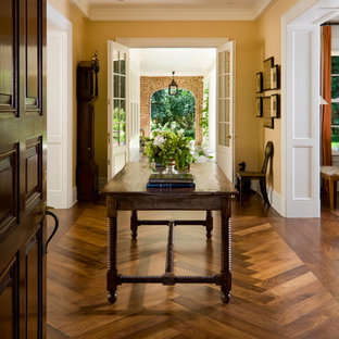 Foto de distribuidor tradicional con paredes amarillas, suelo de madera oscura, puerta simple y puerta de madera oscura