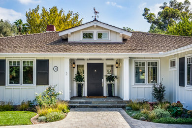 Photo of a large and white traditional bungalow front detached house in Los Angeles with vinyl cladding, a hip roof, a shingle roof, a grey roof and board and batten cladding.