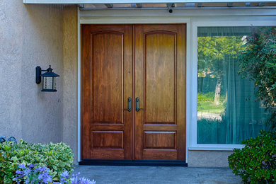 Huge elegant entryway photo in Orange County with brown walls and a medium wood front door