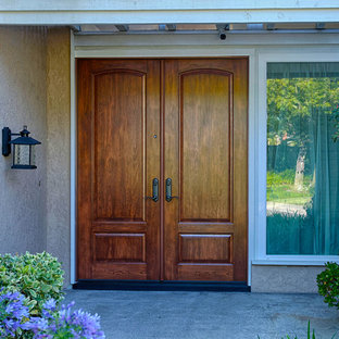 Idée de décoration pour une très grand porte d'entrée tradition avec un mur marron, une porte double et une porte en bois brun.