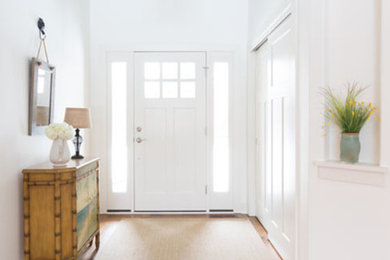Example of a large beach style medium tone wood floor and brown floor entryway design with white walls and a white front door