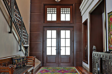 Example of a mid-sized eclectic medium tone wood floor and brown floor entryway design in Miami with beige walls and a dark wood front door