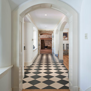 Cette image montre un hall d'entrée rustique avec un mur blanc, une porte simple et un sol multicolore.