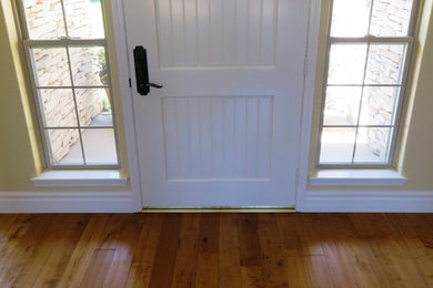 Example of a mid-sized farmhouse light wood floor entryway design in Other with yellow walls and a white front door