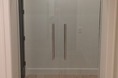 Diseño de distribuidor contemporáneo de tamaño medio con paredes beige, suelo de madera clara, puerta doble, puerta de vidrio y suelo beige