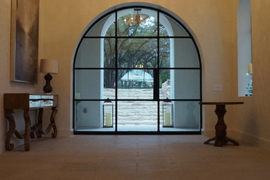 Aménagement d'une grande porte d'entrée contemporaine avec un mur blanc, un sol en calcaire, une porte simple et une porte noire.