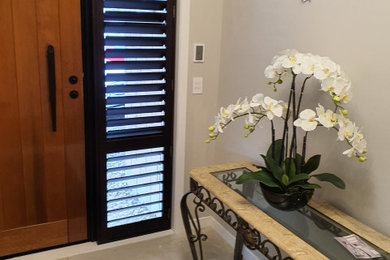 Imagen de distribuidor minimalista con paredes blancas, suelo de baldosas de porcelana, puerta simple y puerta de madera en tonos medios