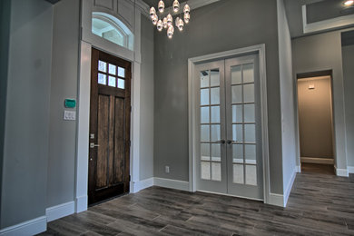 Example of a mid-sized transitional porcelain tile and gray floor entryway design in Dallas with gray walls and a dark wood front door