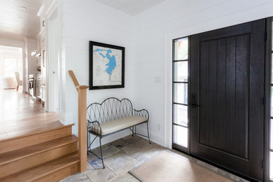 Ejemplo de puerta principal clásica grande con paredes blancas, suelo de pizarra, puerta pivotante y puerta negra