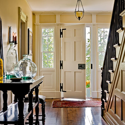 Example of a classic entryway design in New York with yellow walls and a white front door
