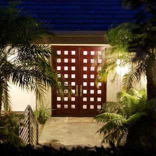 Exemple d'une porte d'entrée exotique de taille moyenne avec un mur blanc, un sol en travertin, une porte double, une porte en bois foncé et un sol beige.