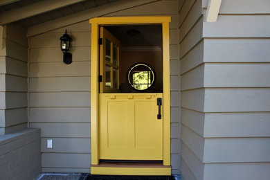 Cette image montre une petite porte d'entrée craftsman avec un mur gris, une porte hollandaise et une porte jaune.