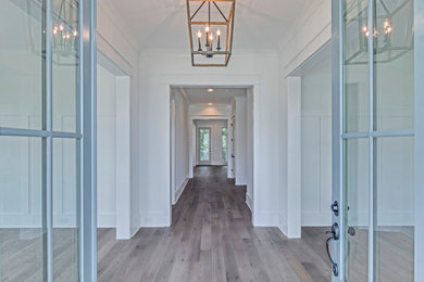 Immagine di un ingresso o corridoio con pareti bianche, parquet chiaro, una porta a due ante e una porta blu
